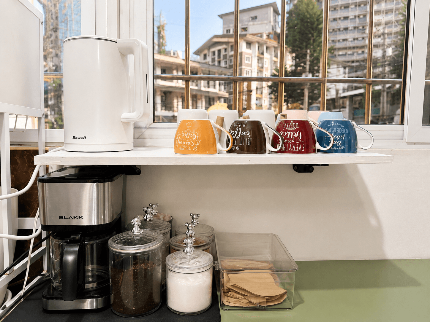 Coffee station with kettle, mugs, drip maker and city-view window