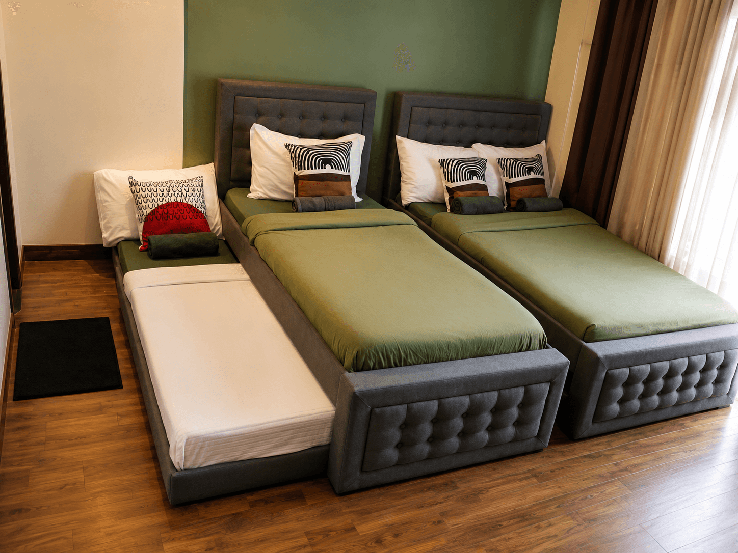 Twin beds with sage green bedding and patterned throw pillows