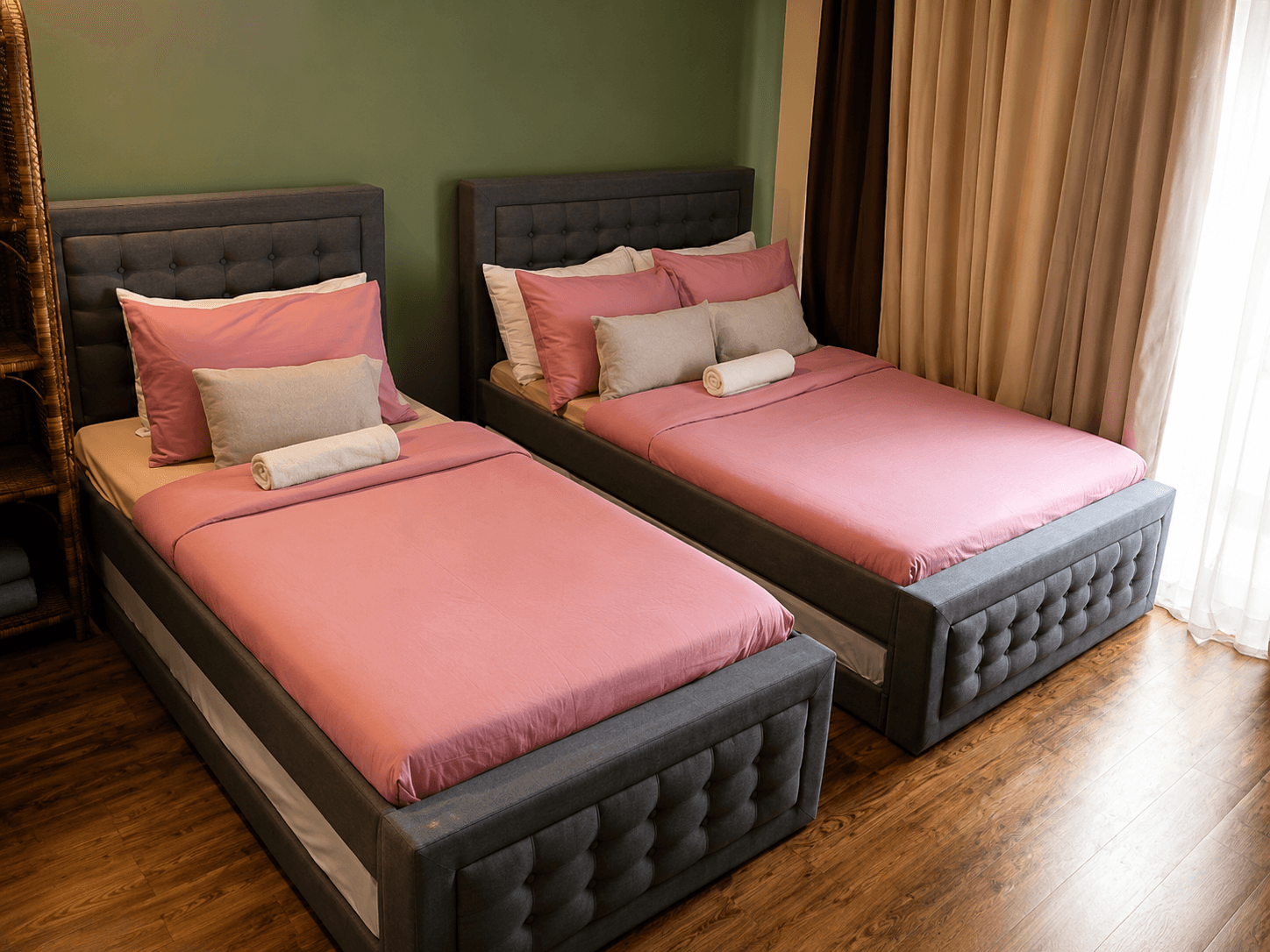 Neatly made twin beds with pink bedding and rolled towels