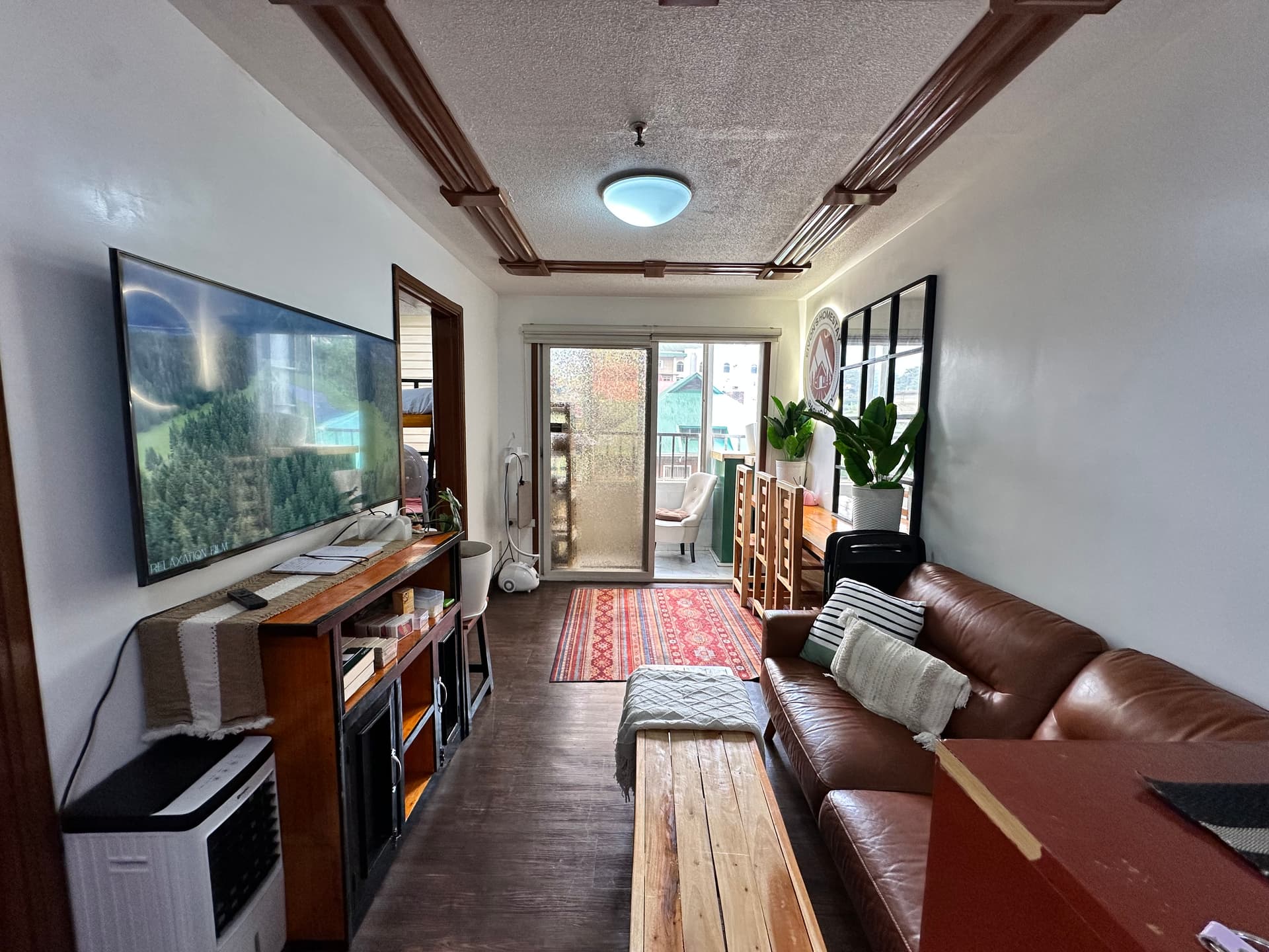 Unit B304 living room with smart TV, leather sofa and balcony access